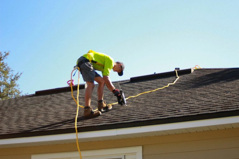 Roofer inspecting a shingle roof, a key factor in Florida home insurance